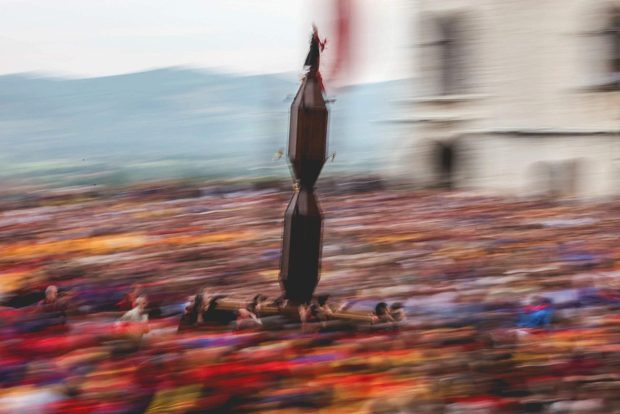 A cero rises above the crowd, blurred by the movement of the race.