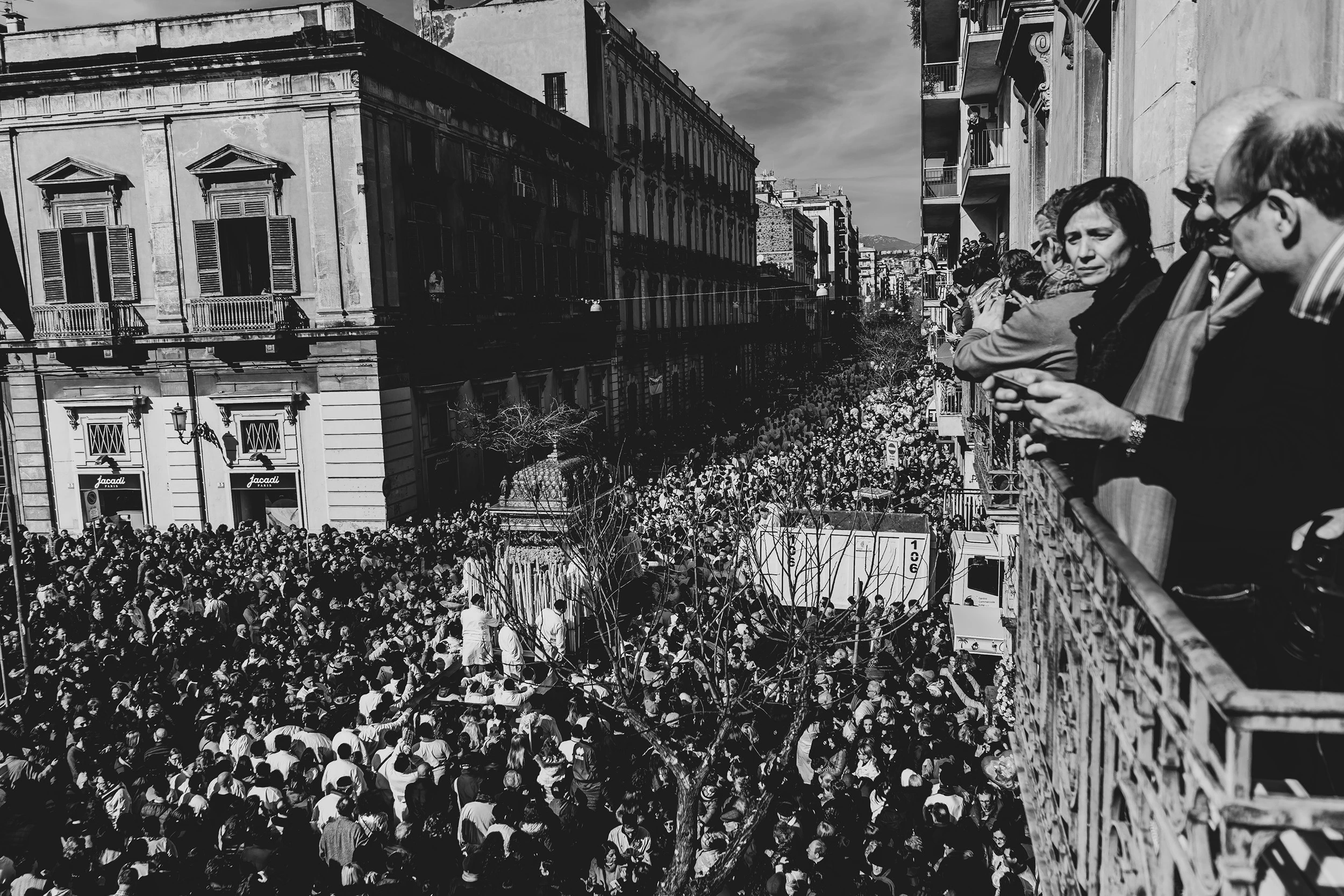 From a balcony, the crowd fills the street between the palaces.
