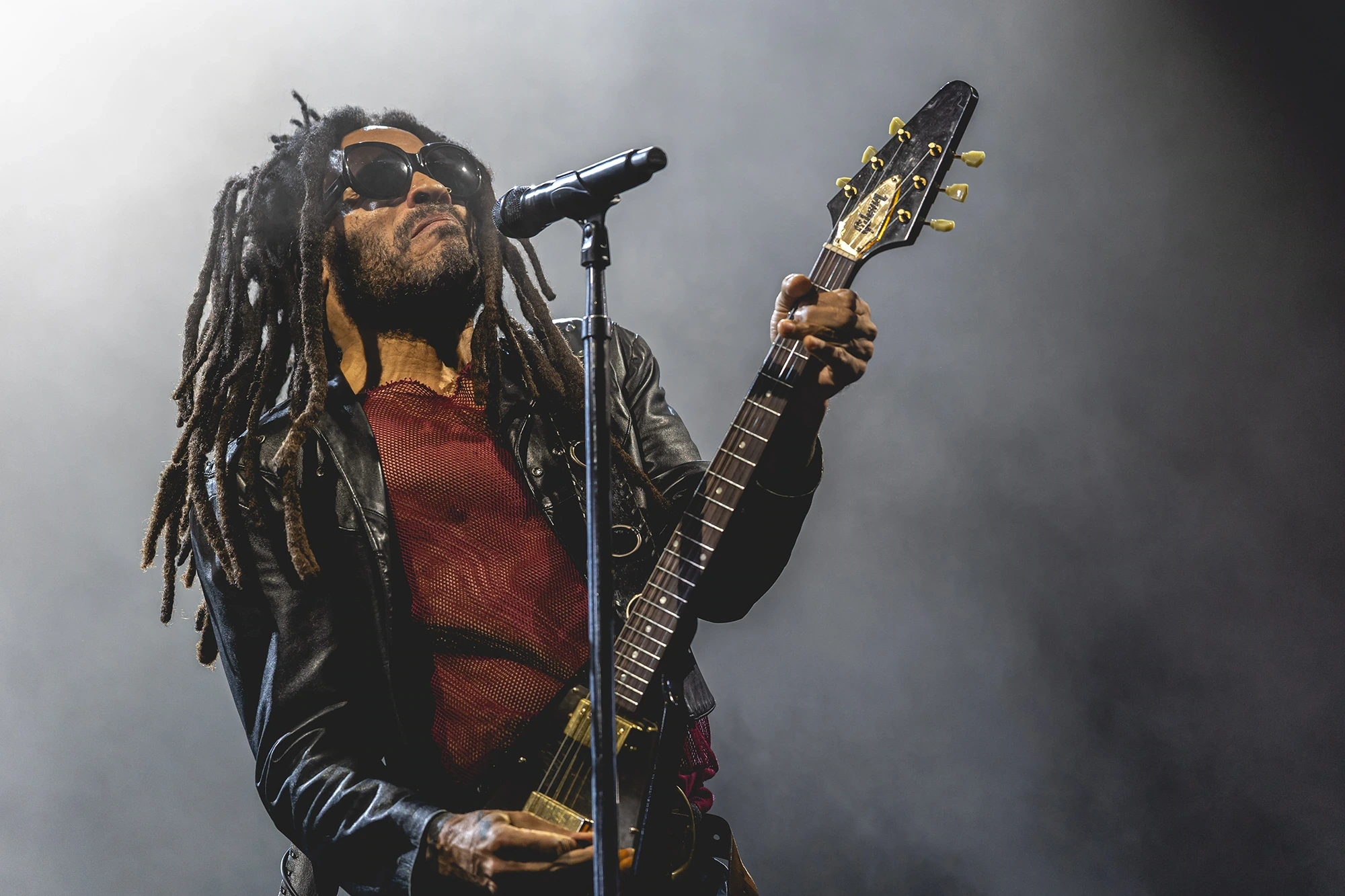 Guitar and microphone backlit through the smoke, in a leather jacket.