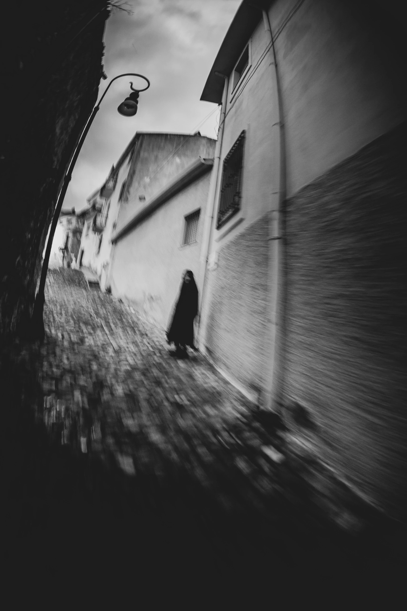 At the end of a blurred alley, a figure dressed in dark clothes.