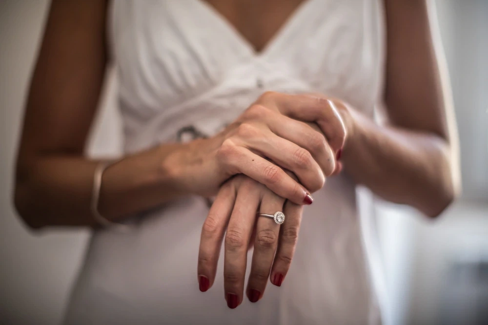 The bride's hands clasped over her dress, the ring on her finger.