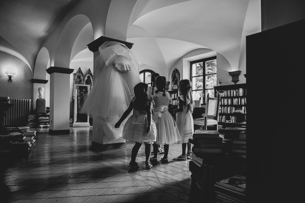 At the far end of the vaulted room, the bride and three girls in white.