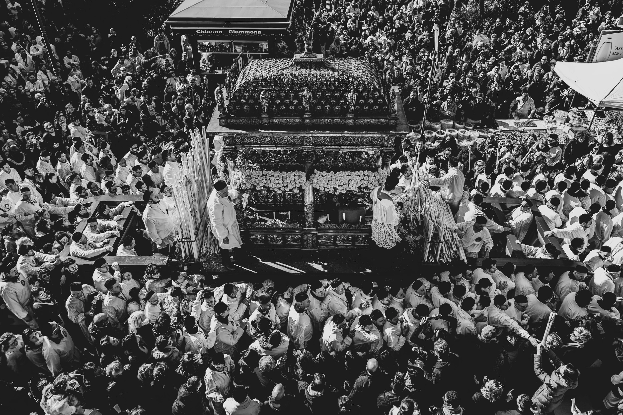 Above the crowd of devotees in white, the flower-decked fercolo moves down the street.