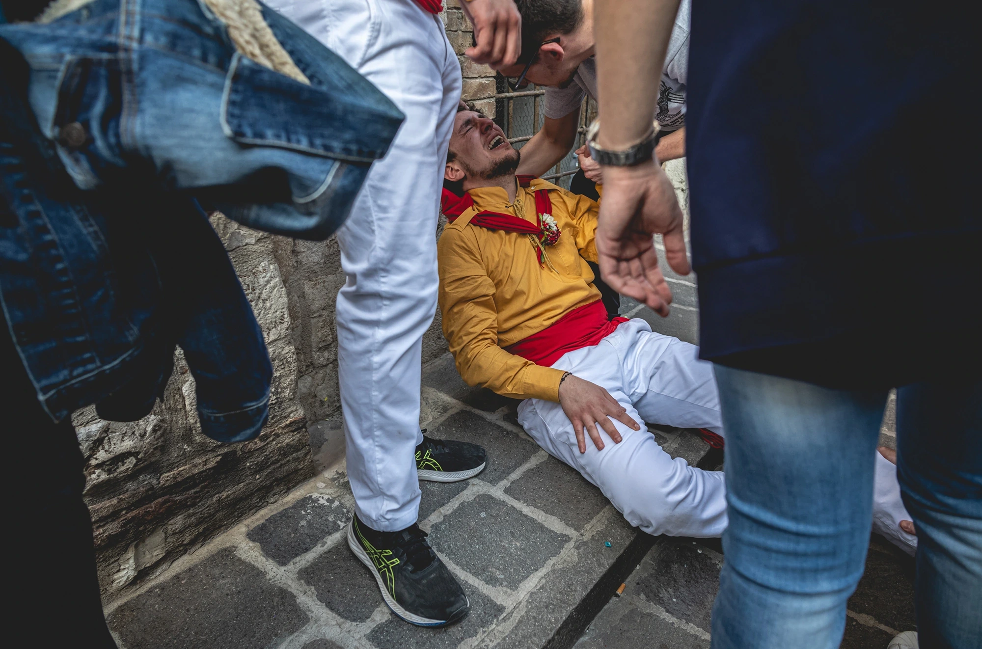 A ceraiolo in a yellow shirt on the ground, held up after the race.