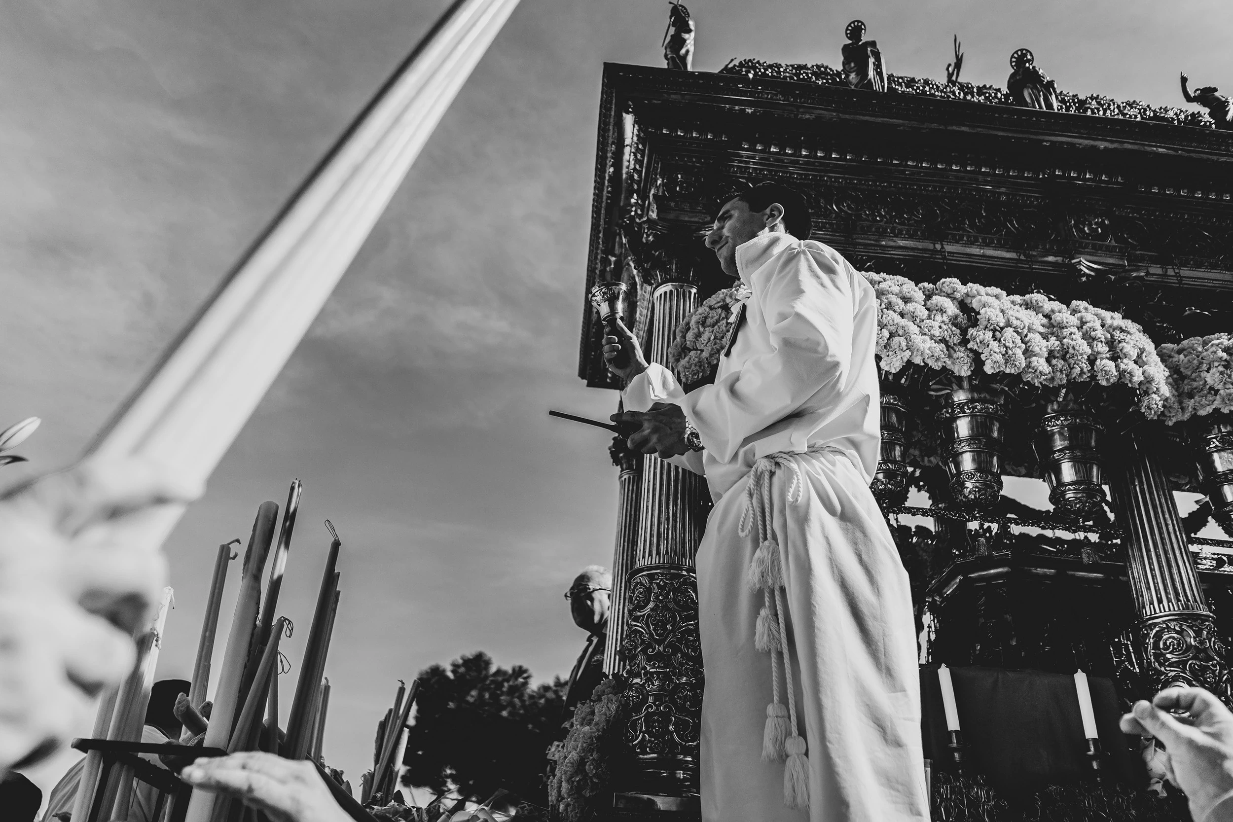Seen from below, a devotee pulls the rope beside the flower-laden fercolo.