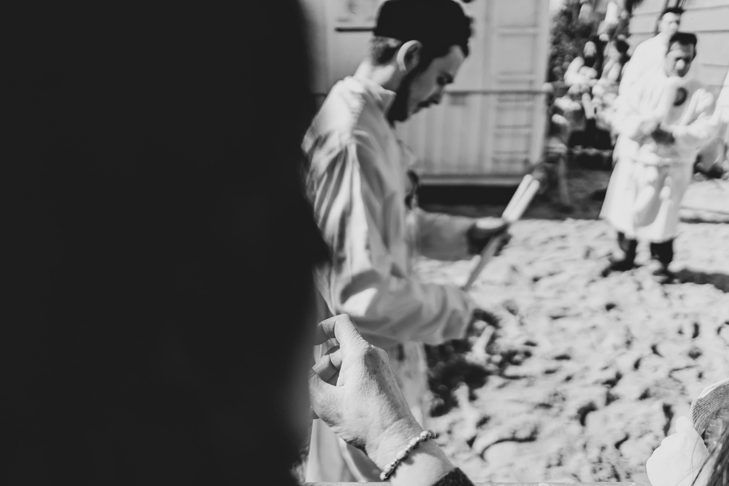 Backlit, a devotee in white walks over the lit cobblestones.