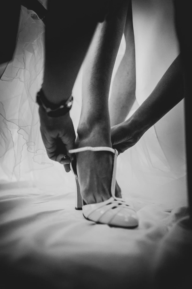 Hands fastening the strap of the sandal.