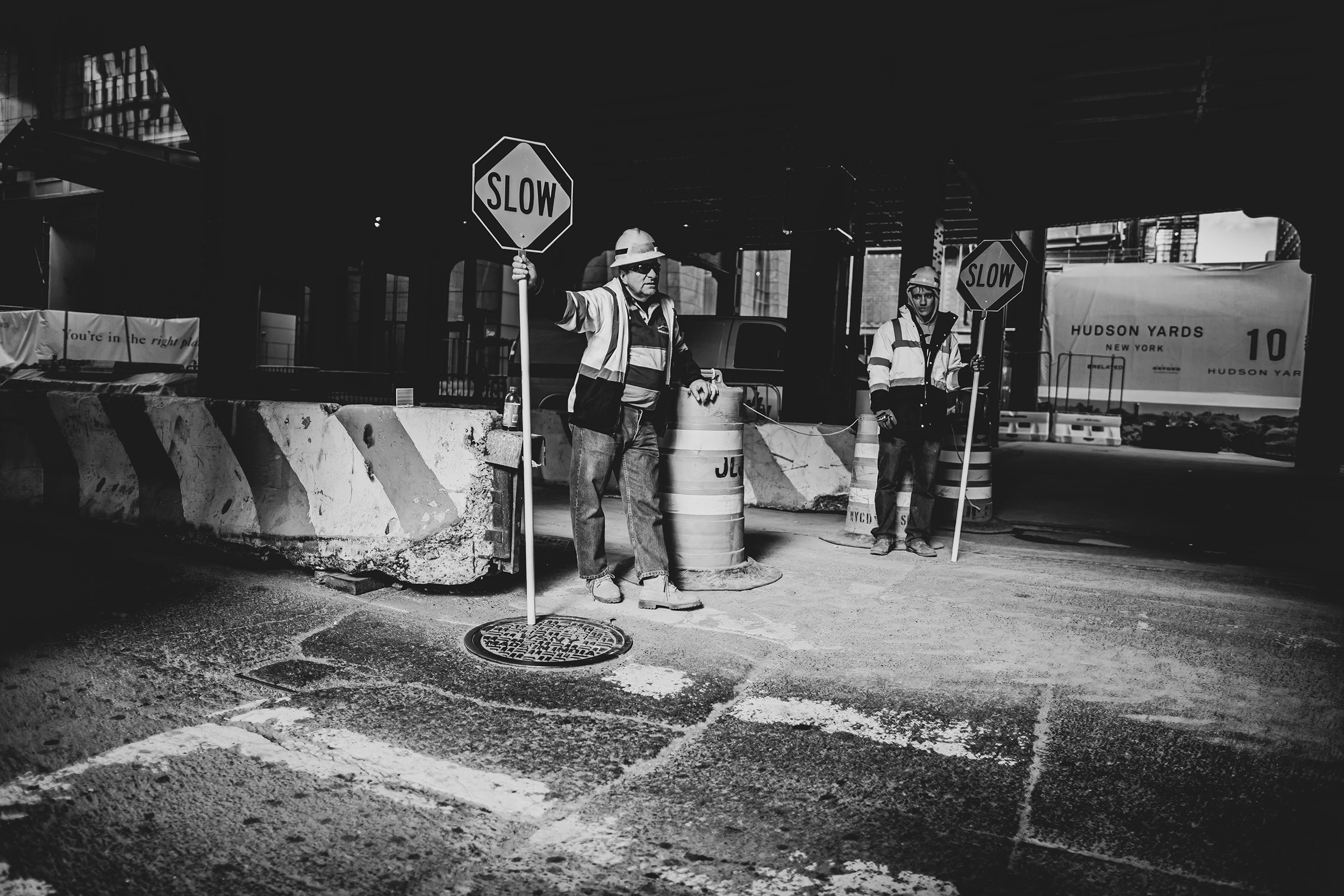 A road worker beside the «slow» sign, among the barriers of a building site.