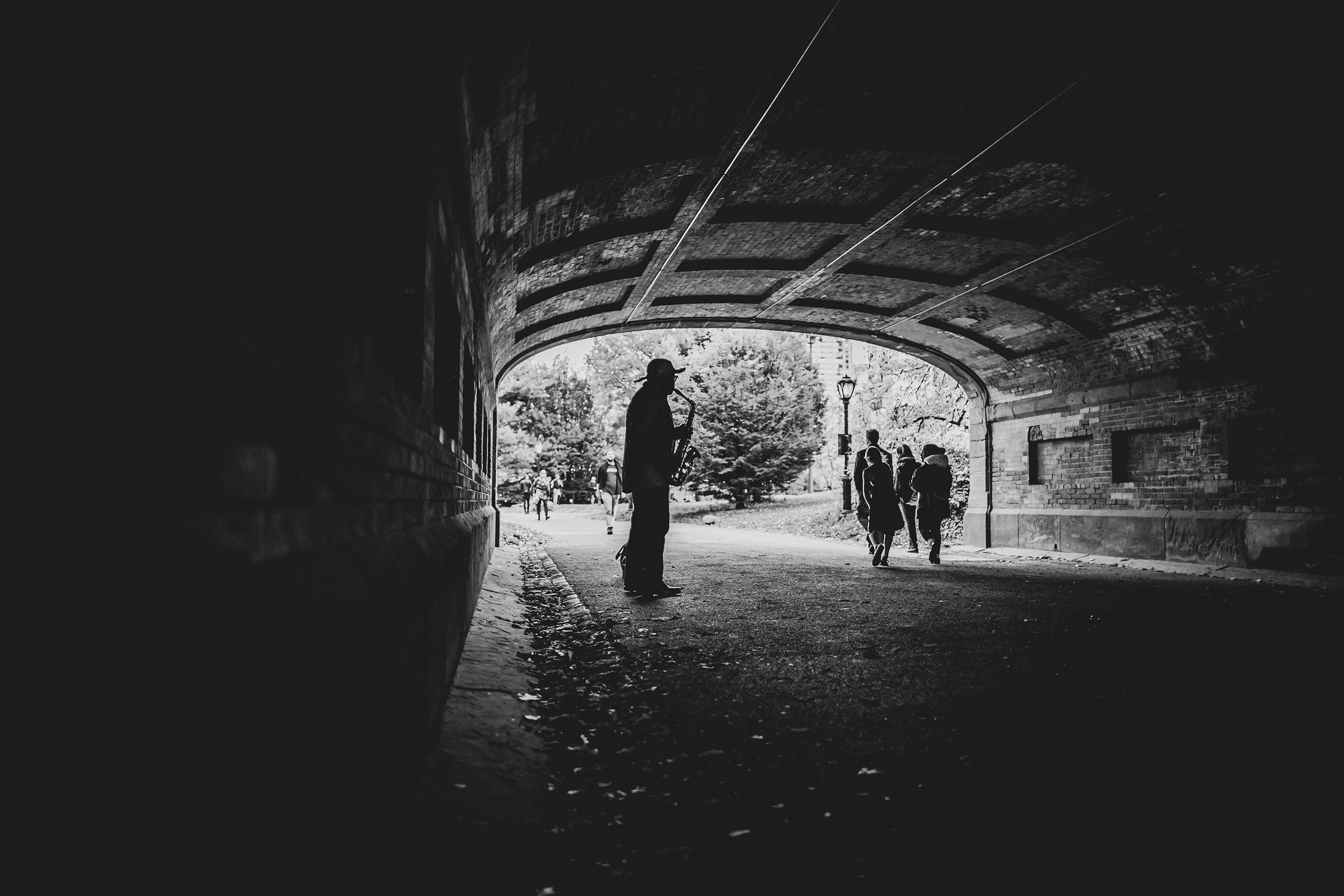 In a dark underpass, a figure silhouetted against the park beyond.