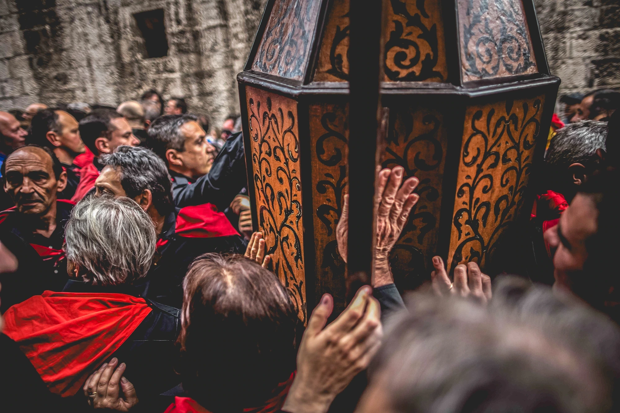 The hands of the crowd press against the decorated body of the cero.