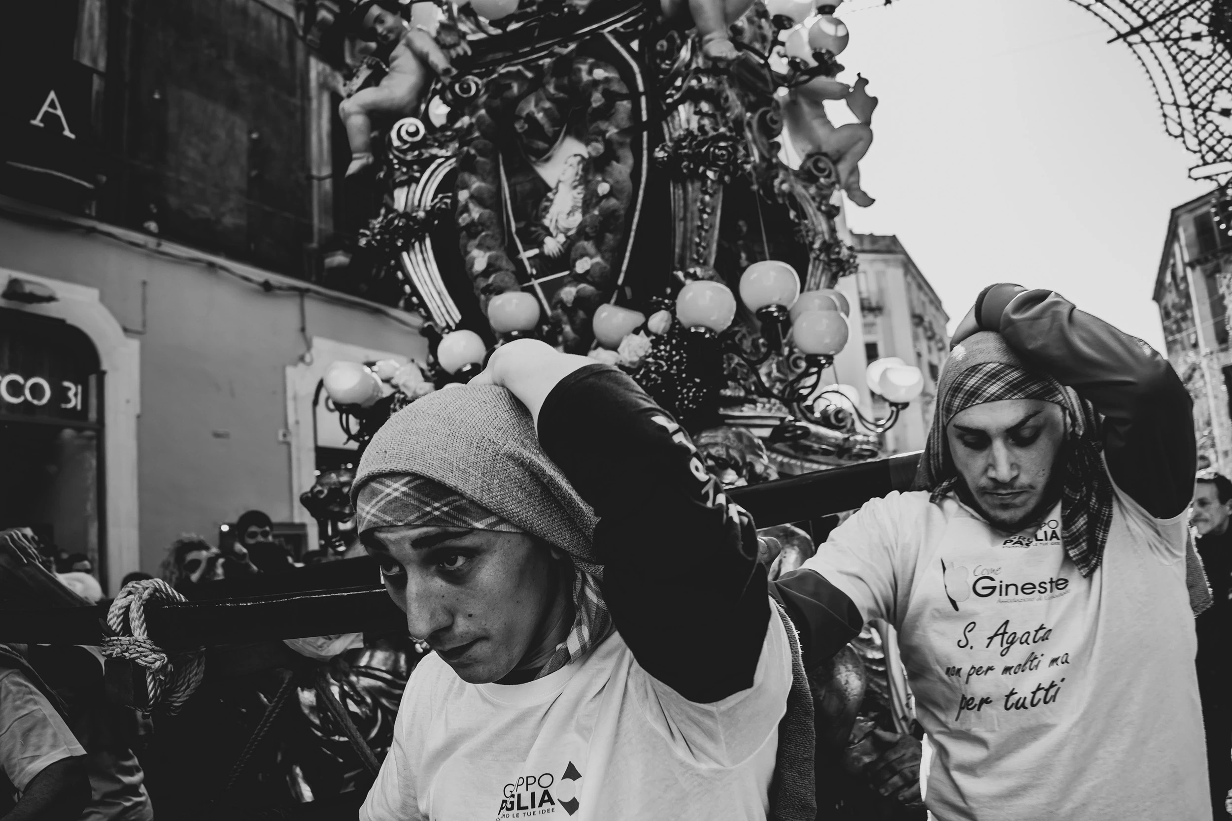 Young men in white T-shirts beneath a lit candelora.