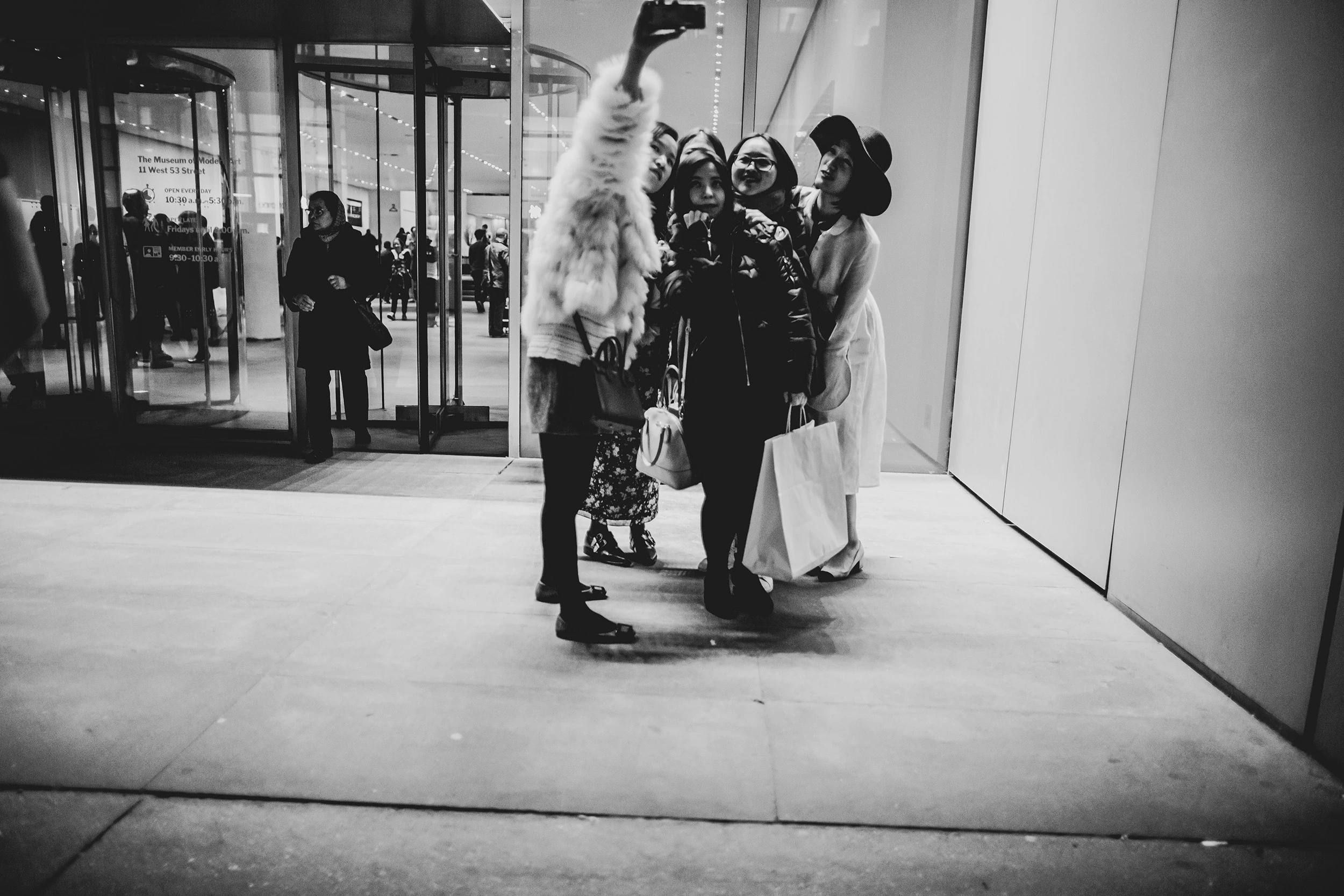 A group of women posing for a photo in front of a lit entrance.