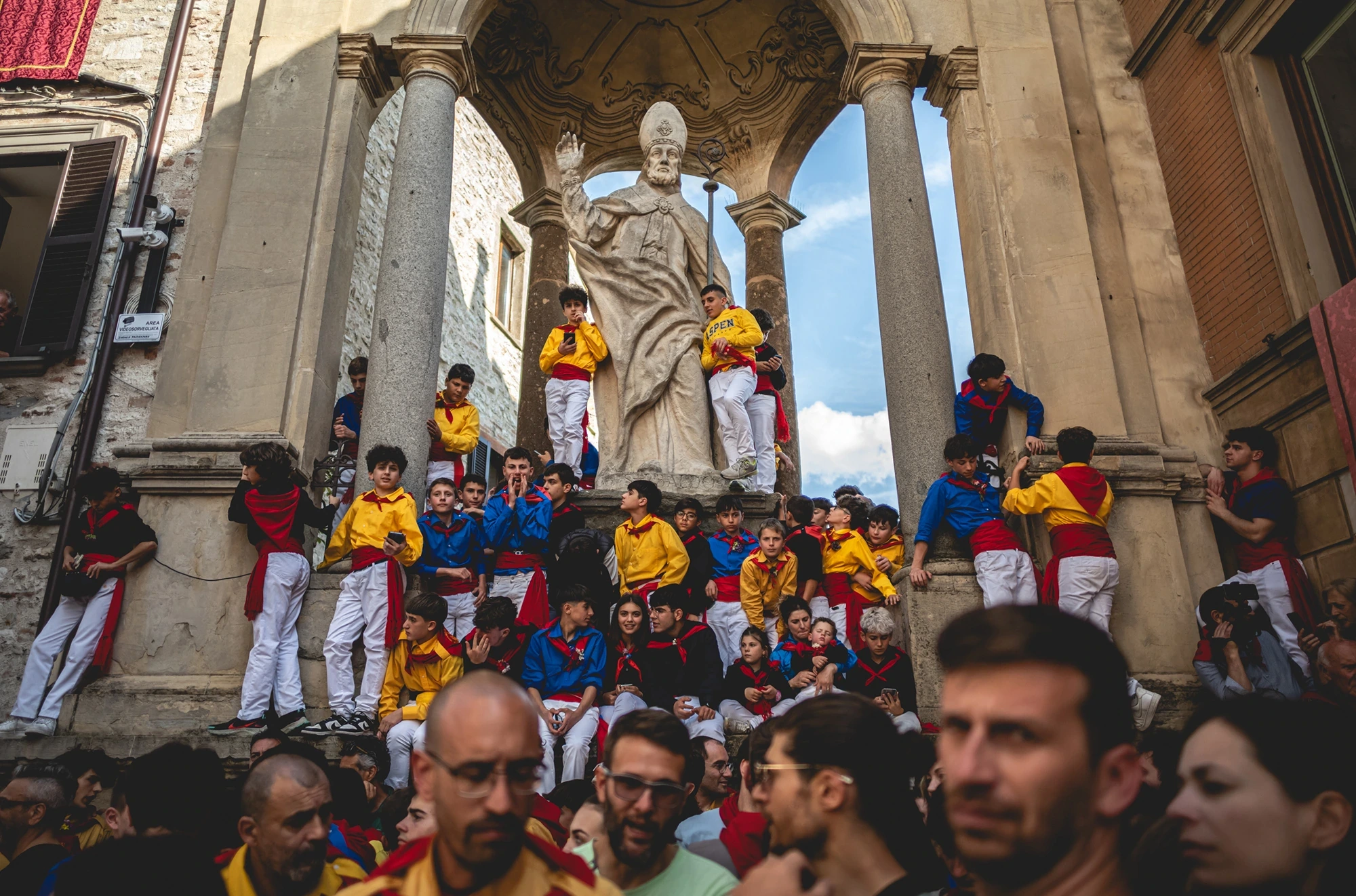 Under the loggia, before the statue of the saint, the ceraioli in yellow.