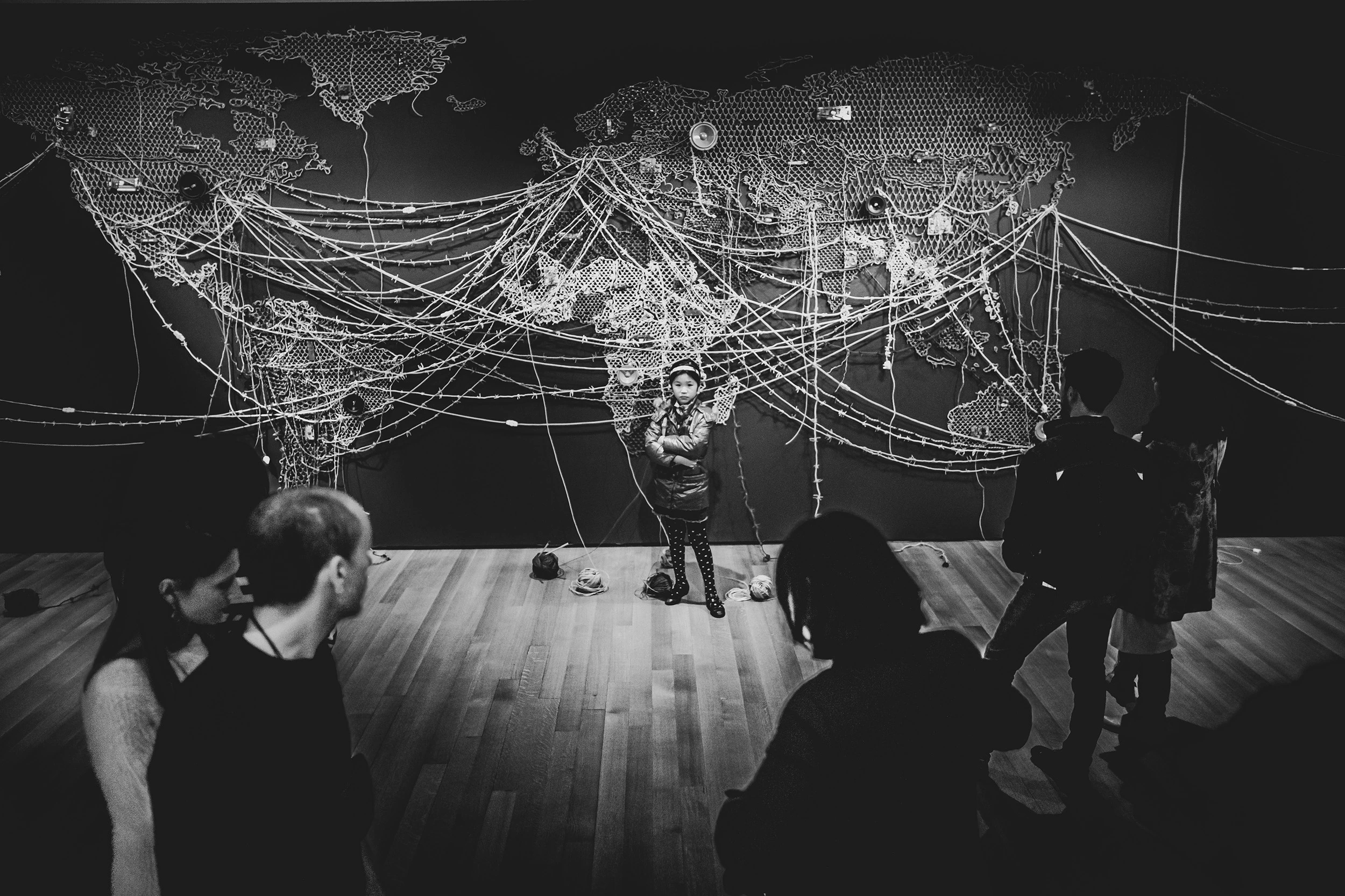 In an exhibition room, visitors in front of a large illuminated world map.