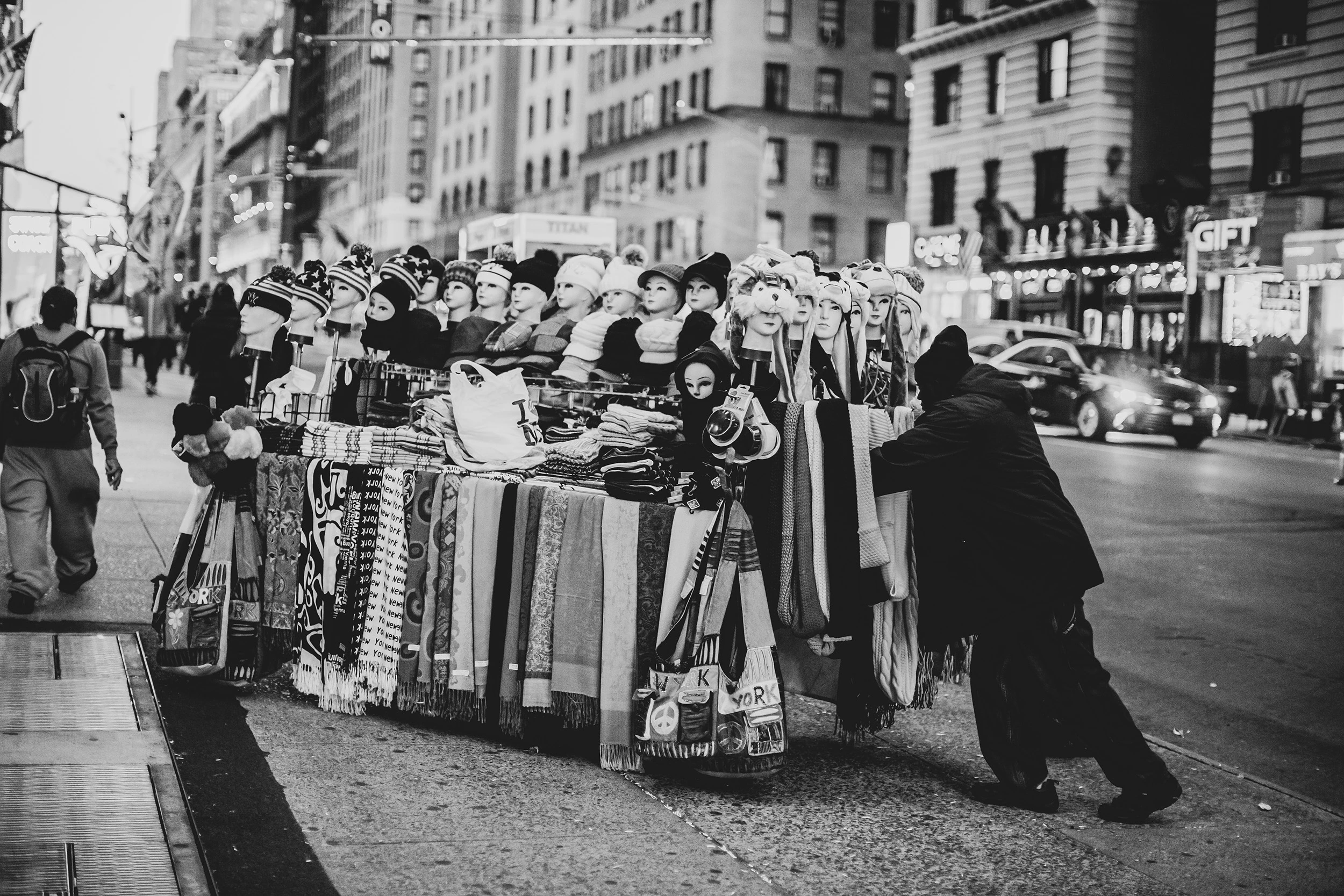 A stall crammed with hats and scarves on the pavement.
