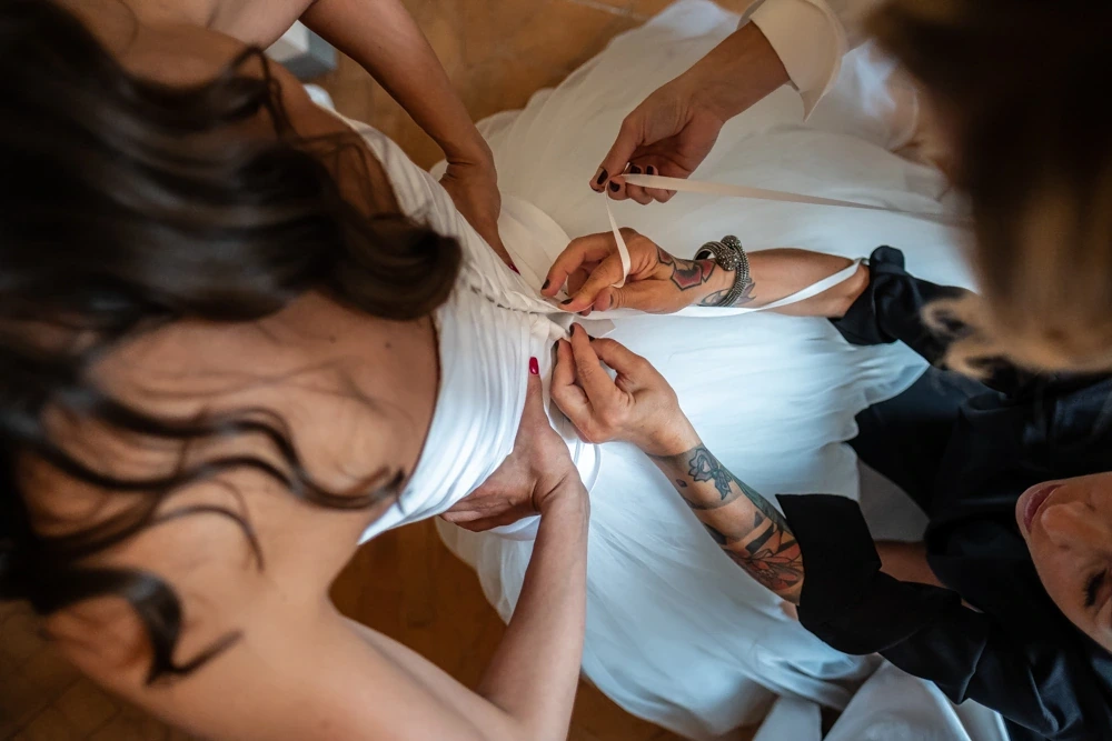From above, hands lacing the back of the dress.