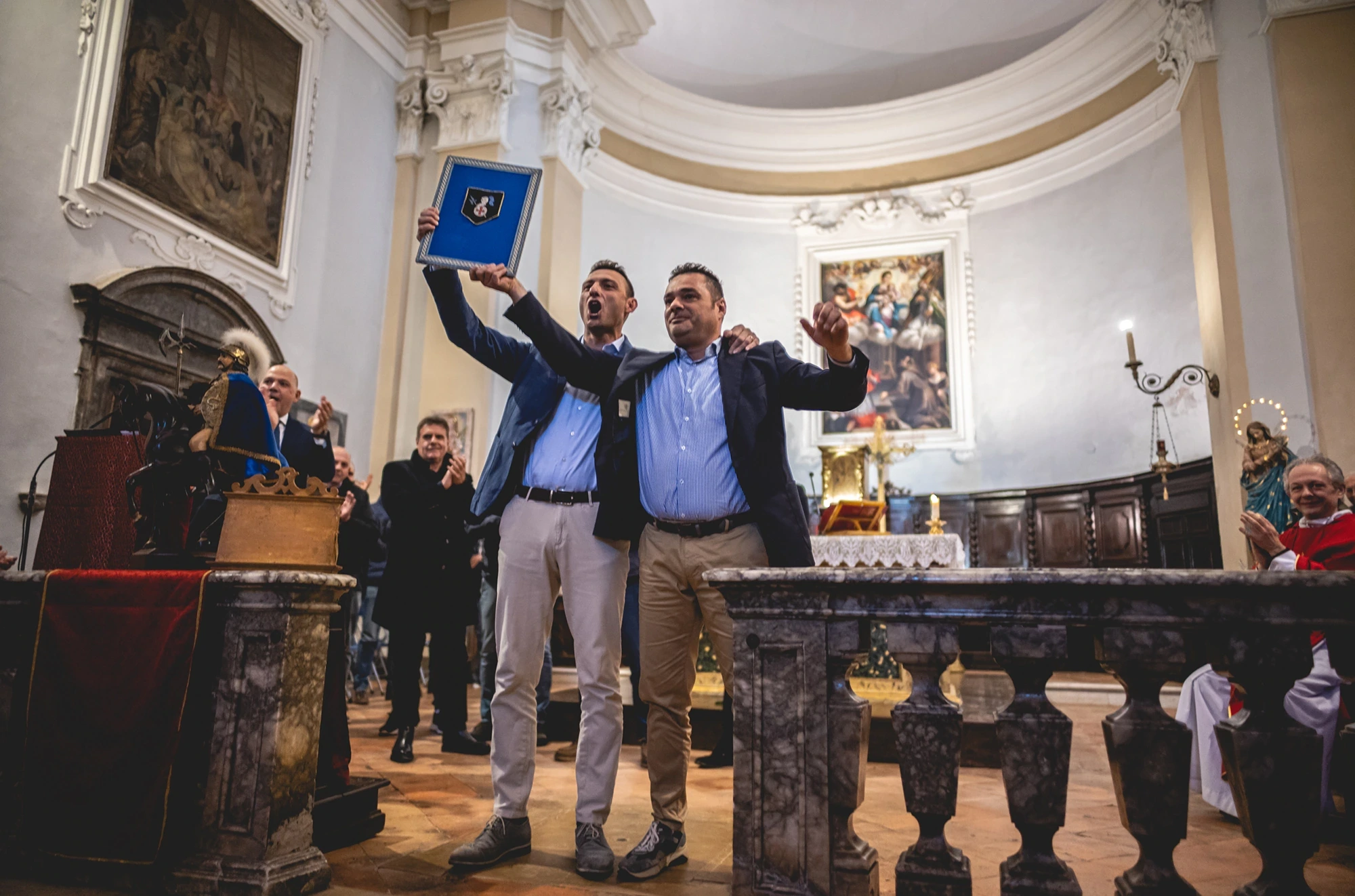In church, two men raise a casket before the altar.