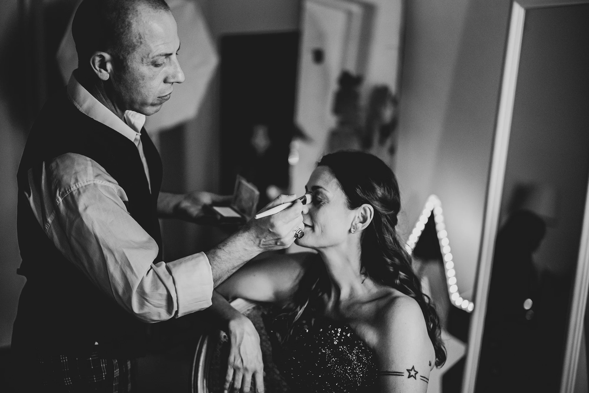 The make-up artist works on her lips, brush in hand.
