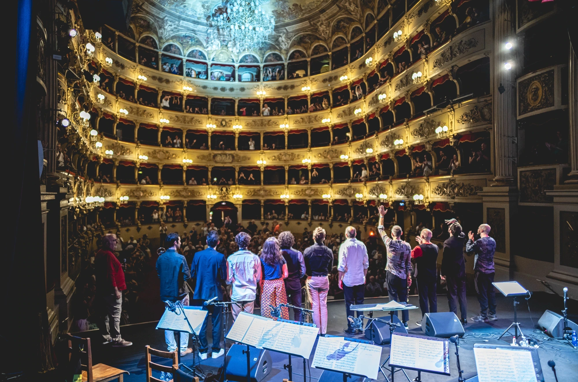 From the stage, the full theatre and the musicians standing to take the applause.