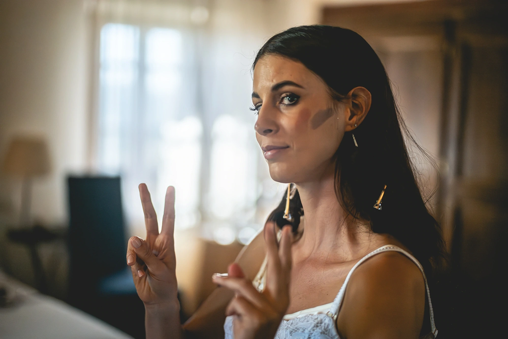 She makes a victory sign while her earring is put on.