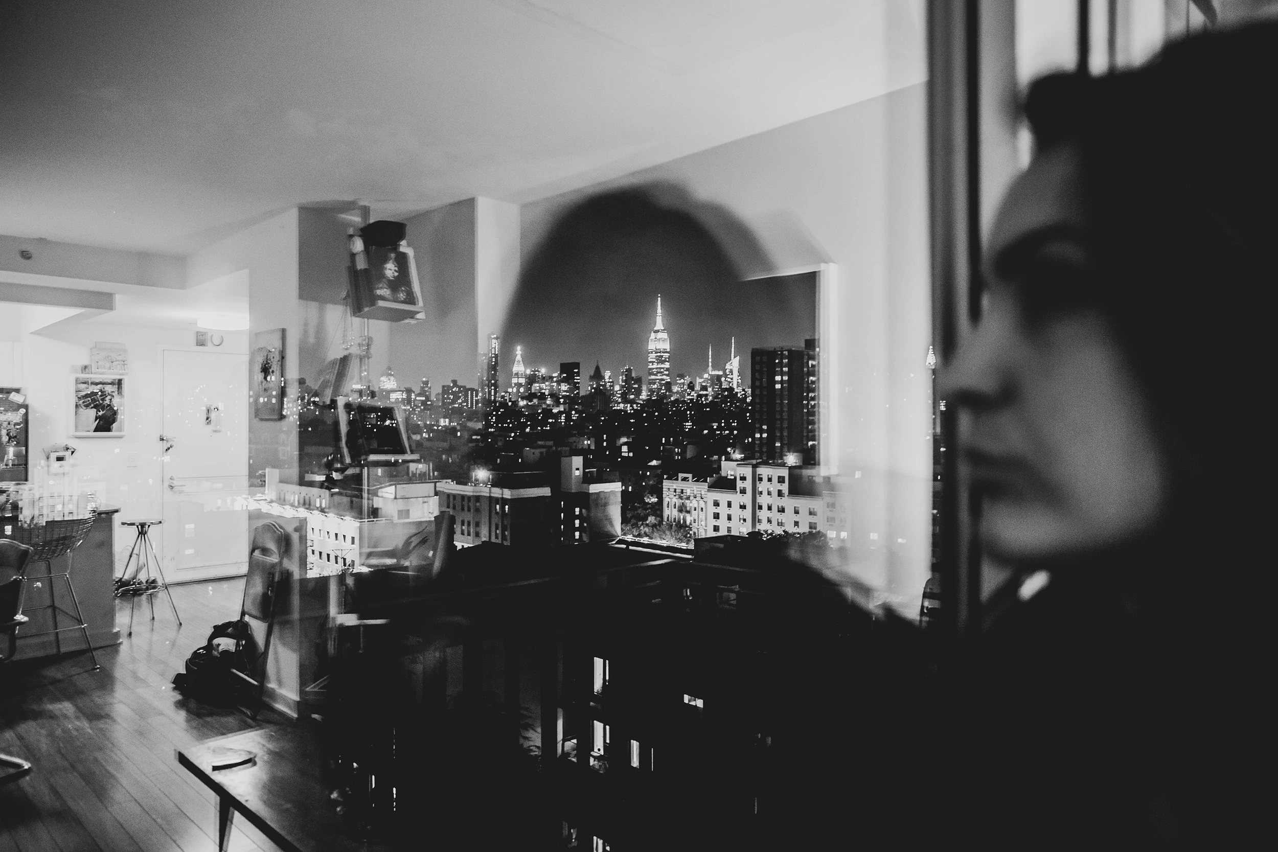 In the foreground a woman's profile; beyond the glass, the skyline.