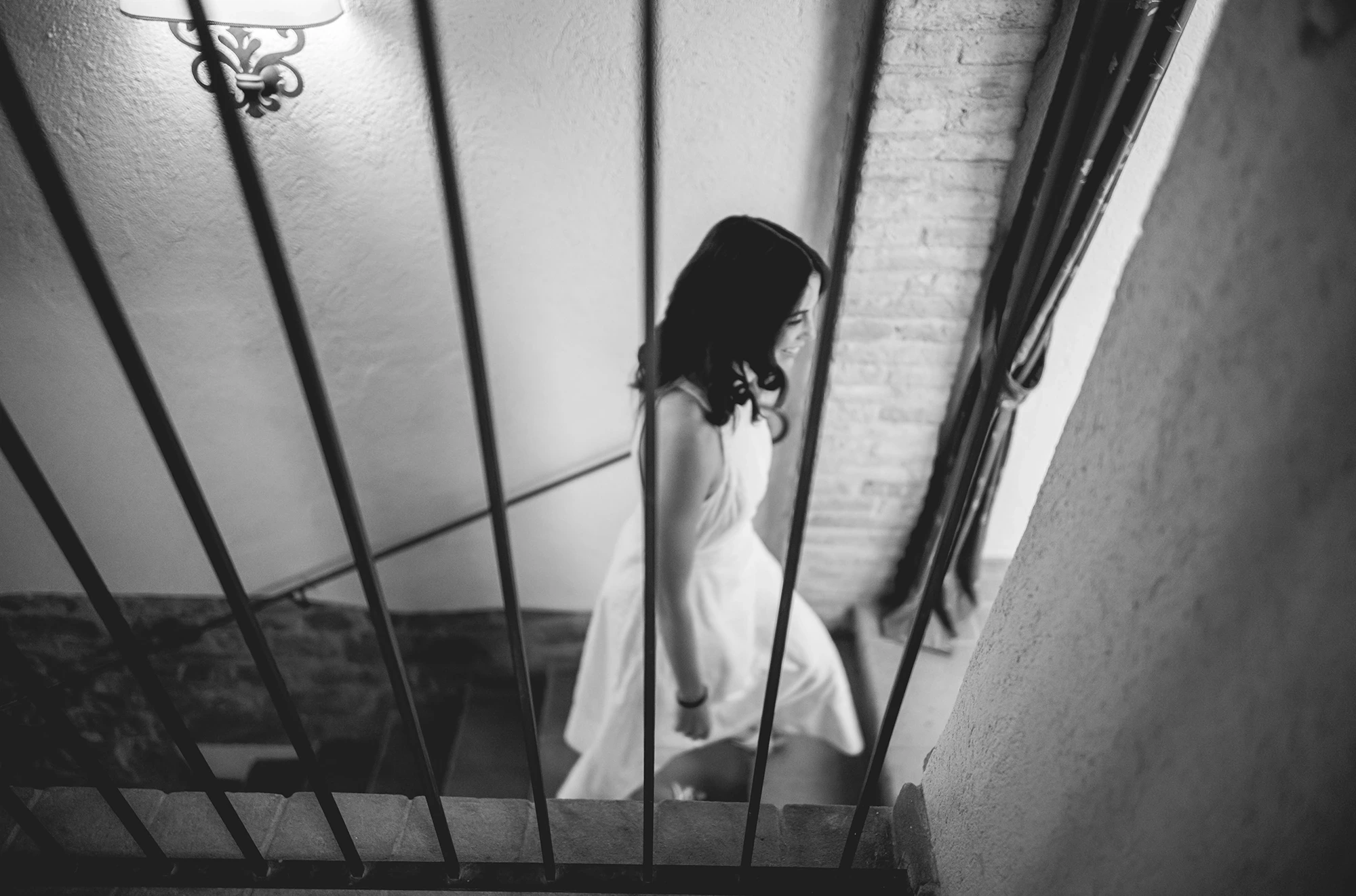 Beyond the stair rail, the bride sitting on the steps.