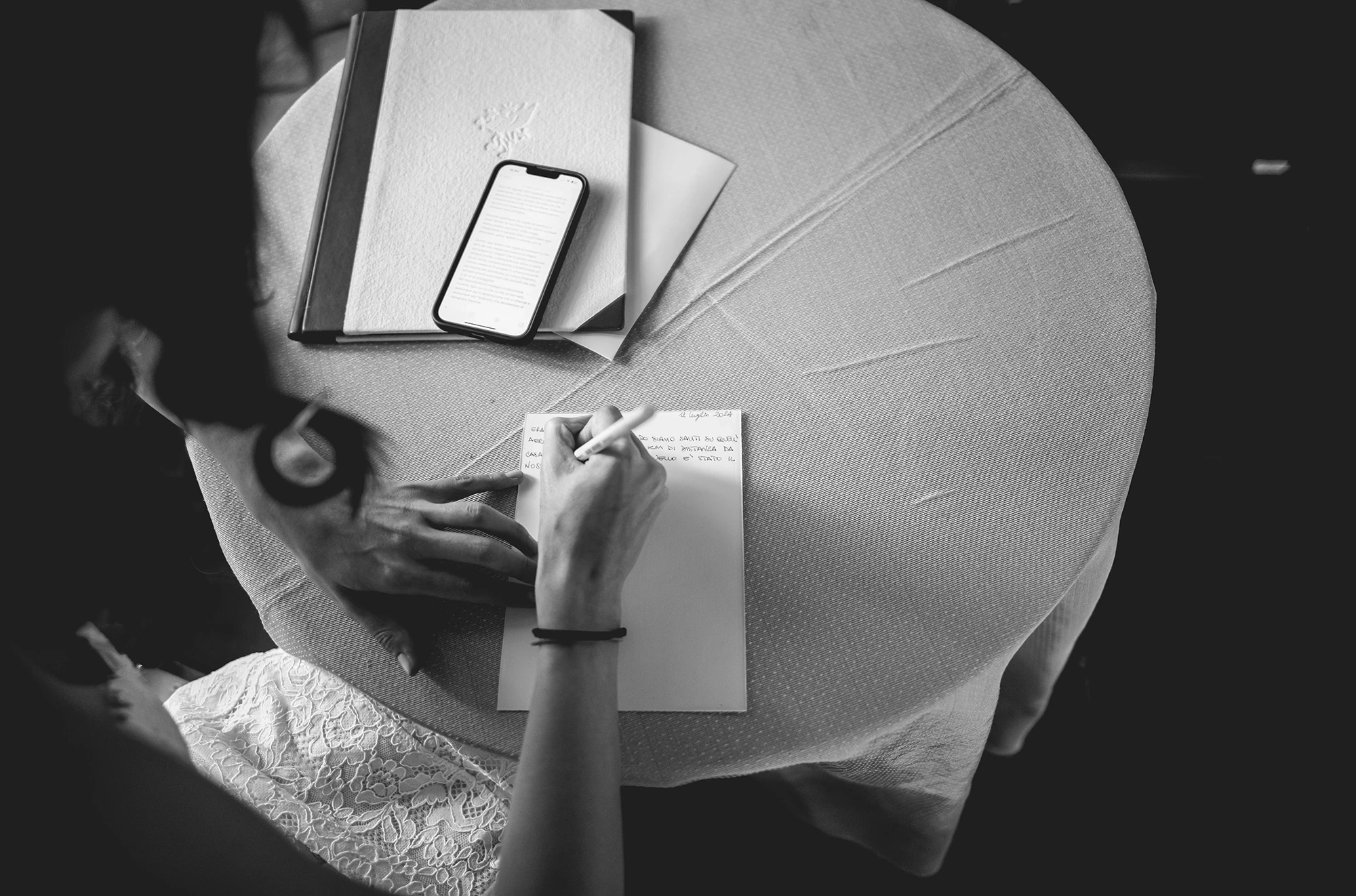 From above, a hand writing a note on the round table.