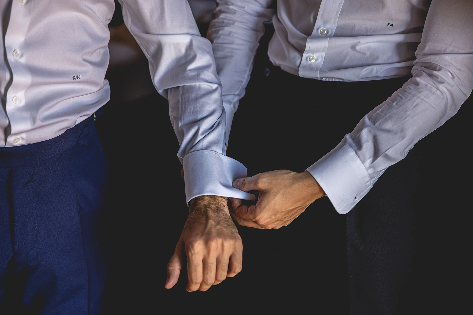 Hands closing the cufflink at the groom's wrist.