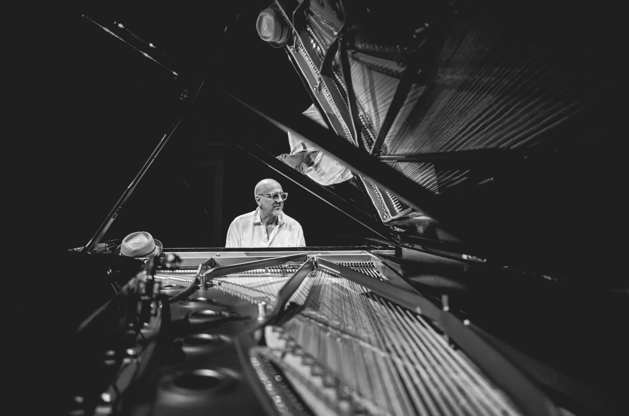 Through the strings of the open piano, the pianist at his place.