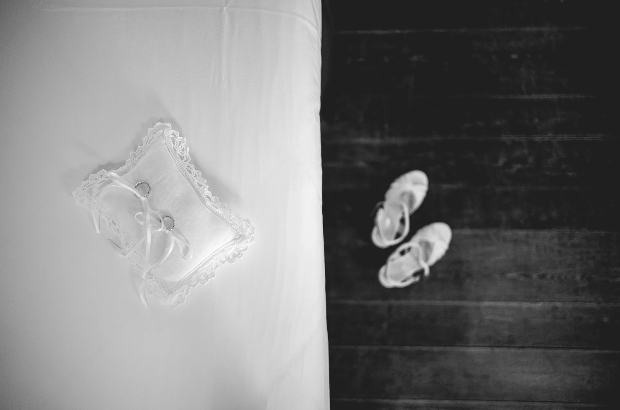 The ring cushion on the sheet, beside the shoes on the dark floor.