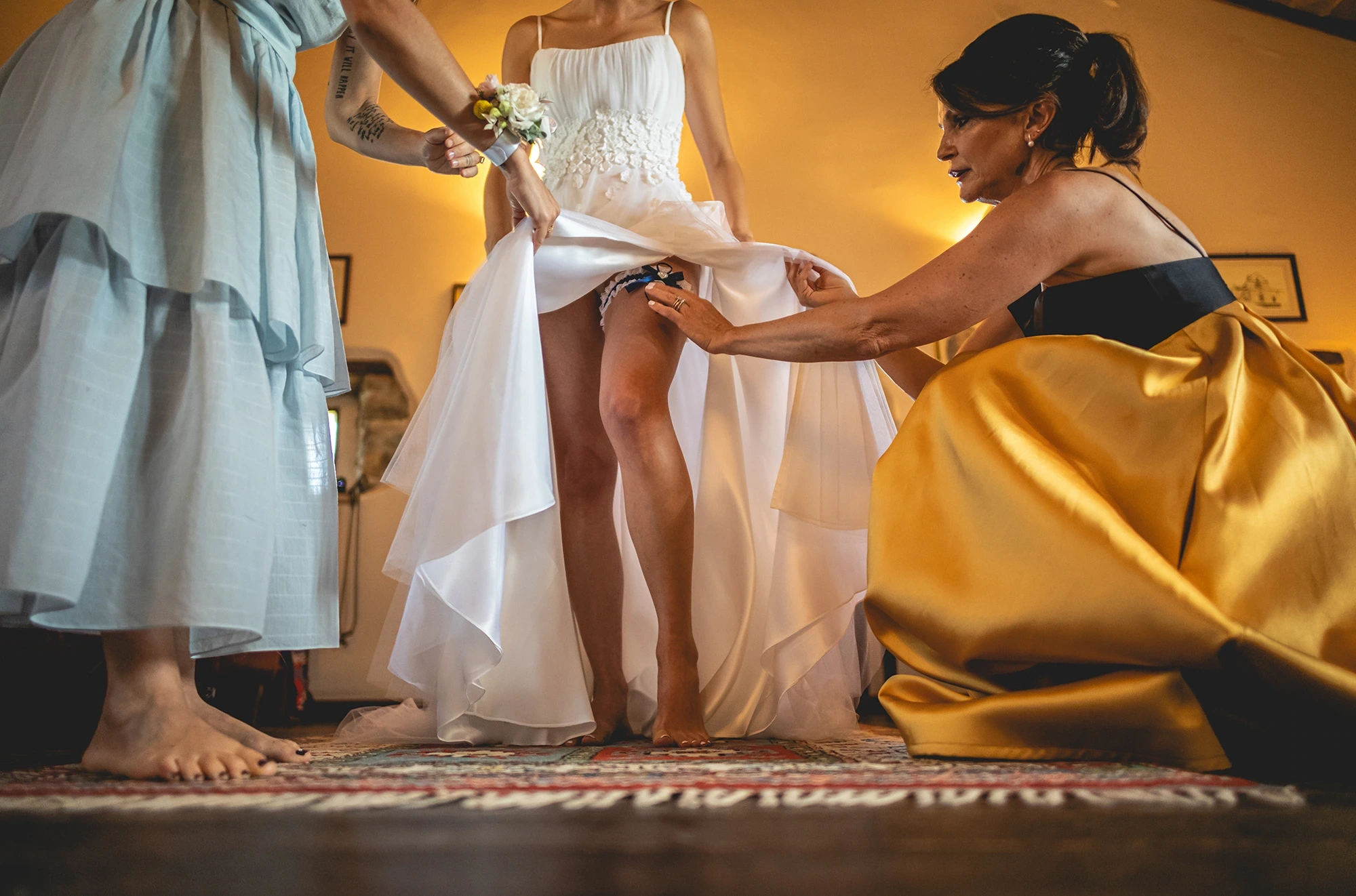 Lifting the dress, a woman in yellow adjusts something beneath the skirt.