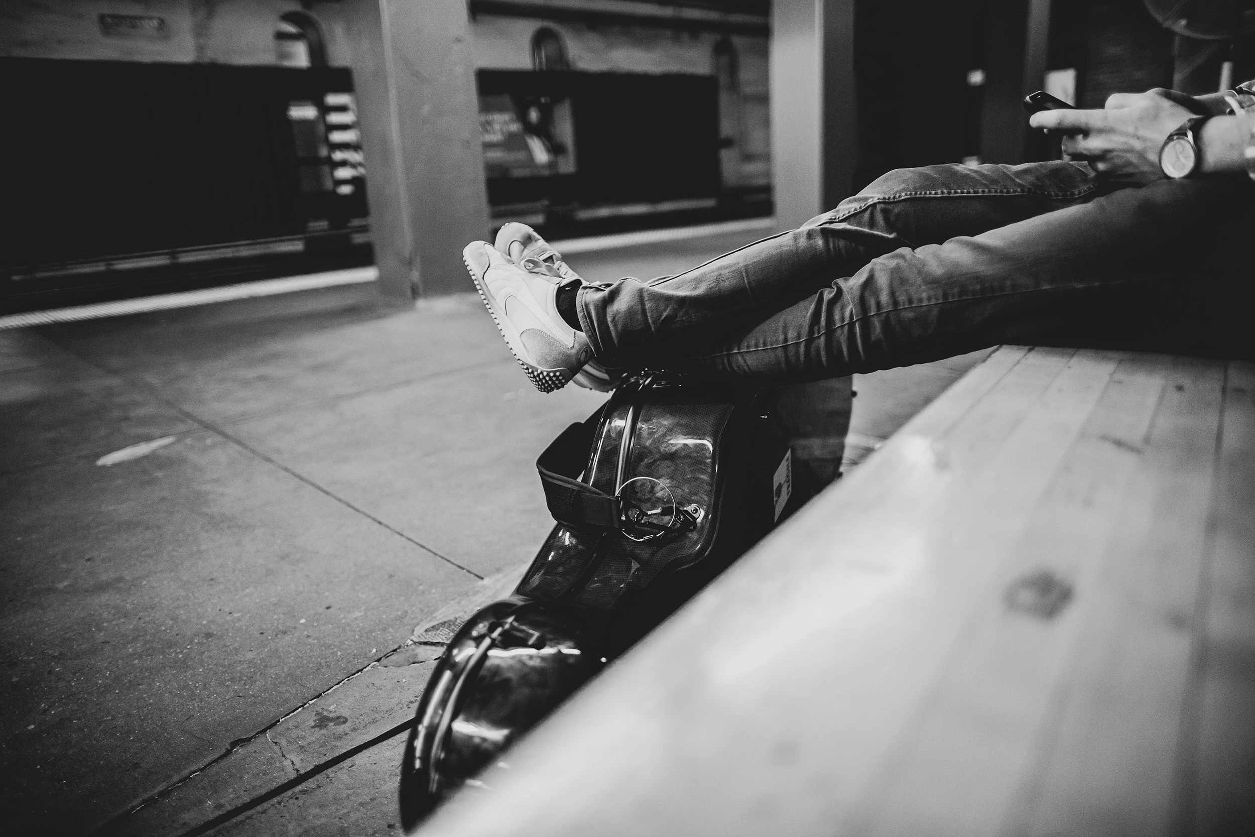 Someone's legs stretched out along a wooden bench.
