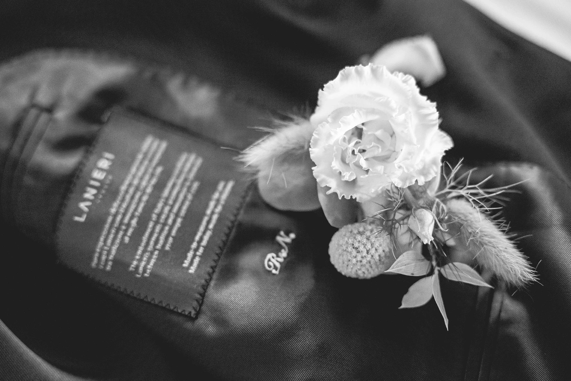 The buttonhole flower on the jacket, beside the tailor's label.