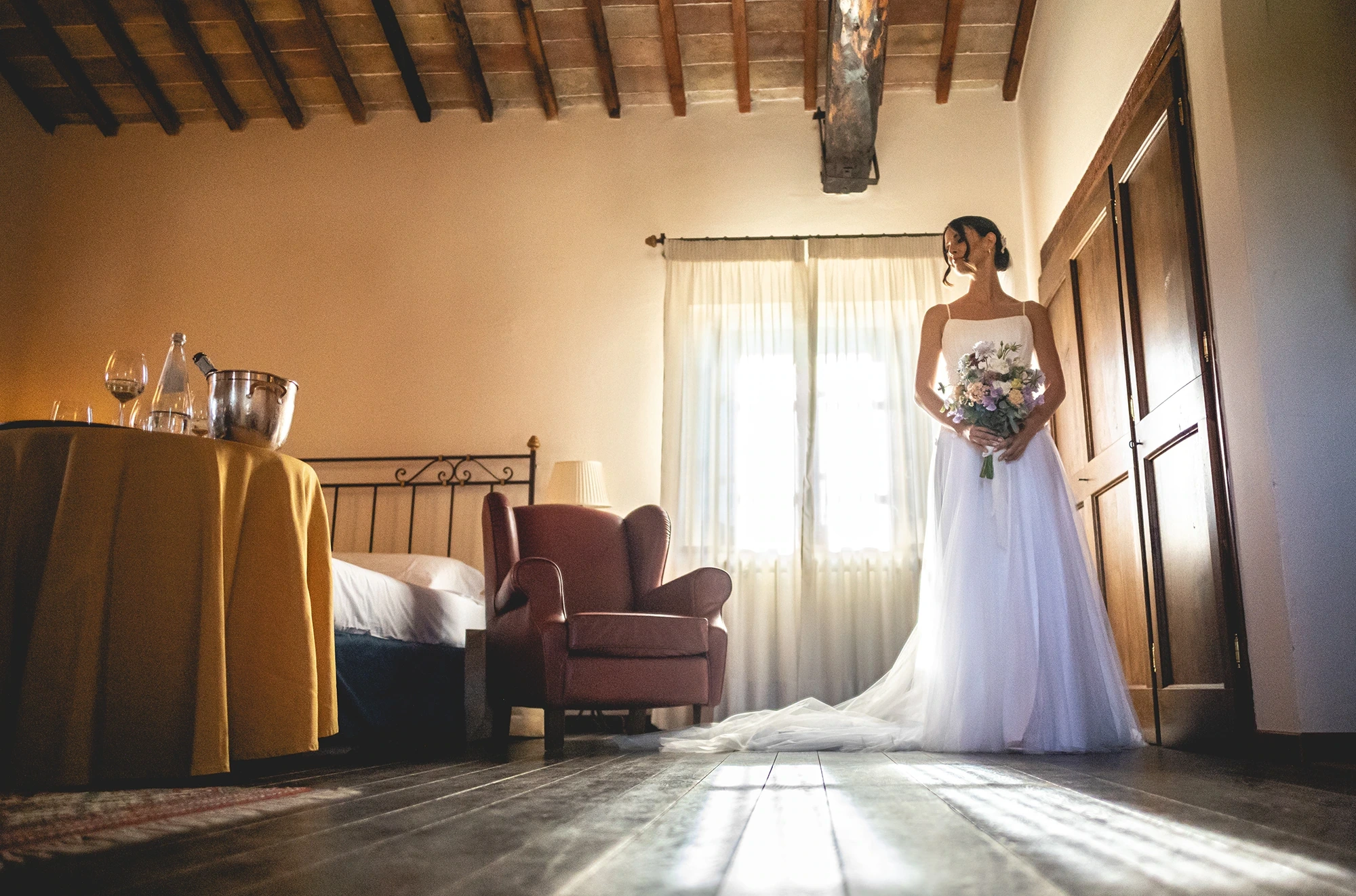 Alone in the room, the bride with her bouquet, the long veil across the floor.