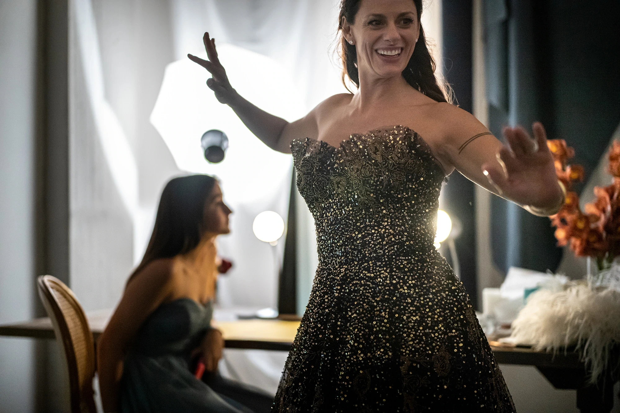 In a black sequinned dress, laughing with open arms.
