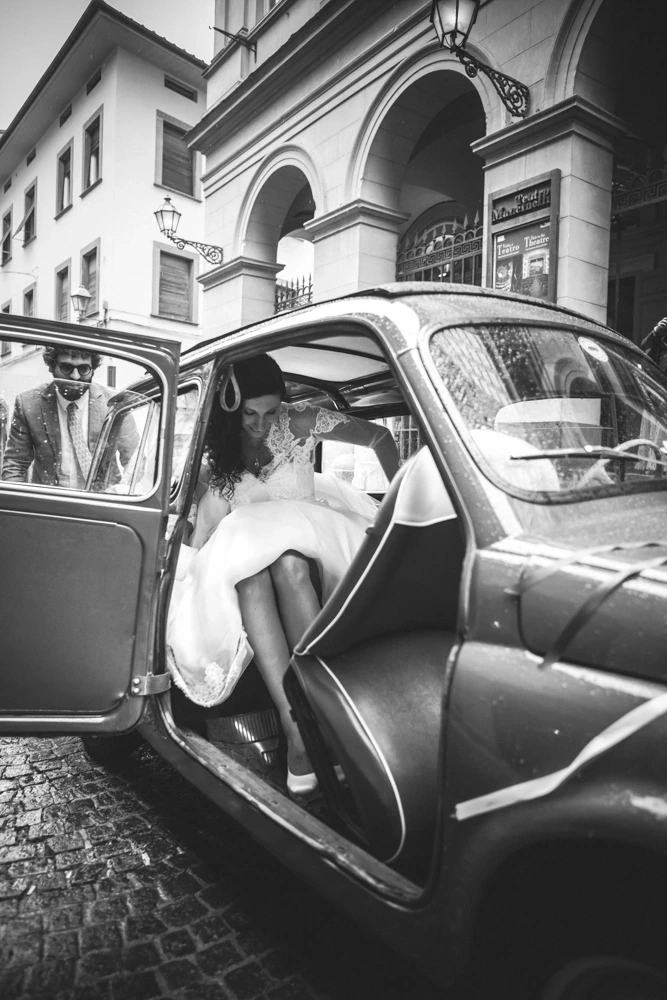 The bride gets into a small vintage car, before the portico.