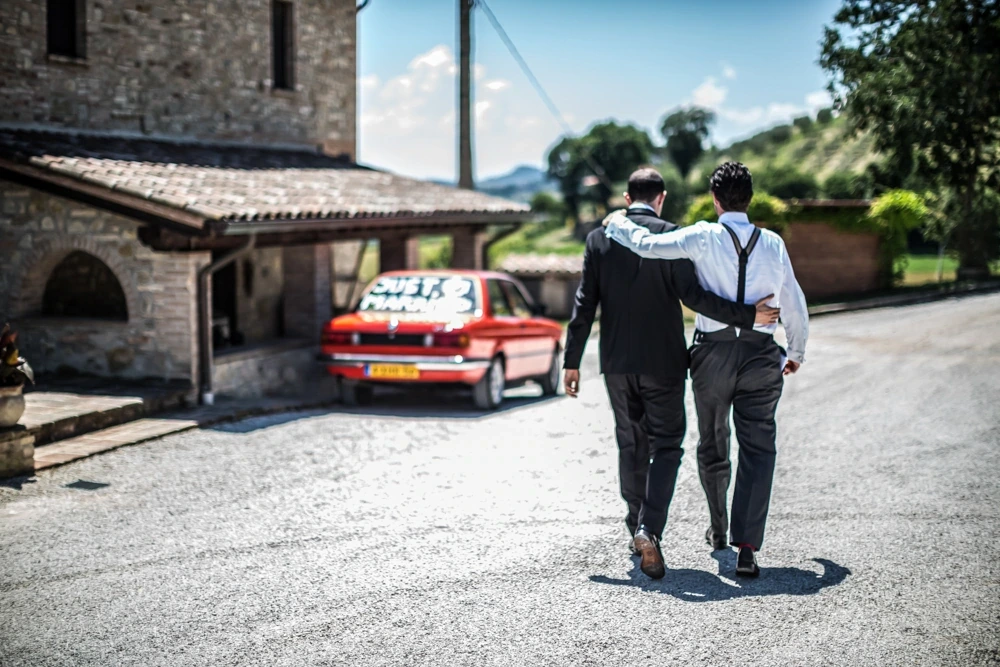 From behind, two men in braces heading for the decorated car.