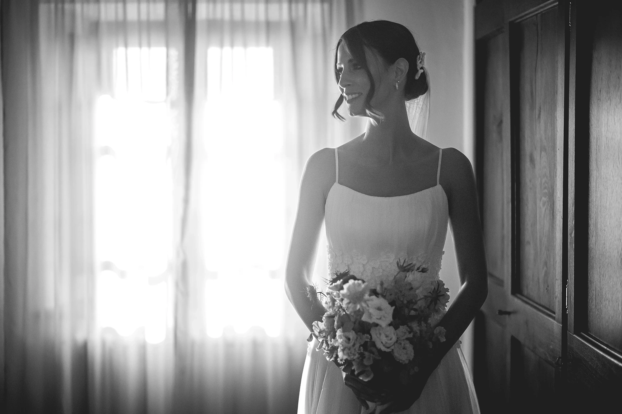 Beside the window, the bride with the bouquet in her hands.