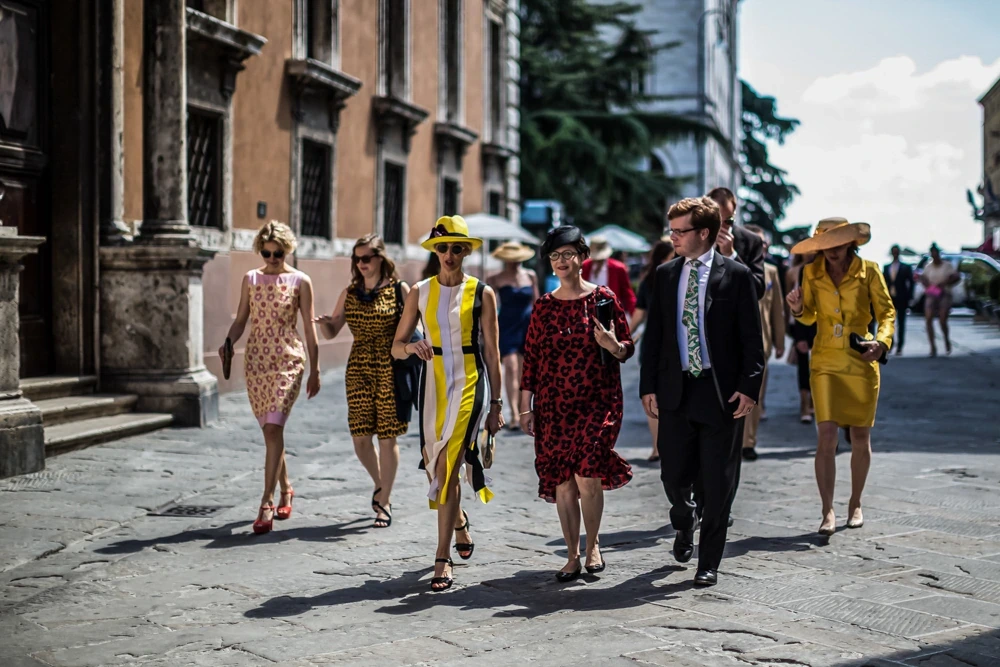 The guests cross the old street in full sunlight.