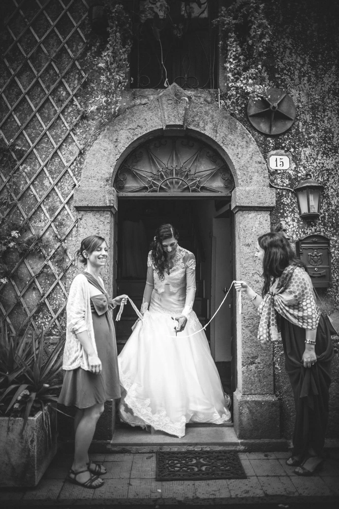 In the doorway, two women hold the train of the dress.