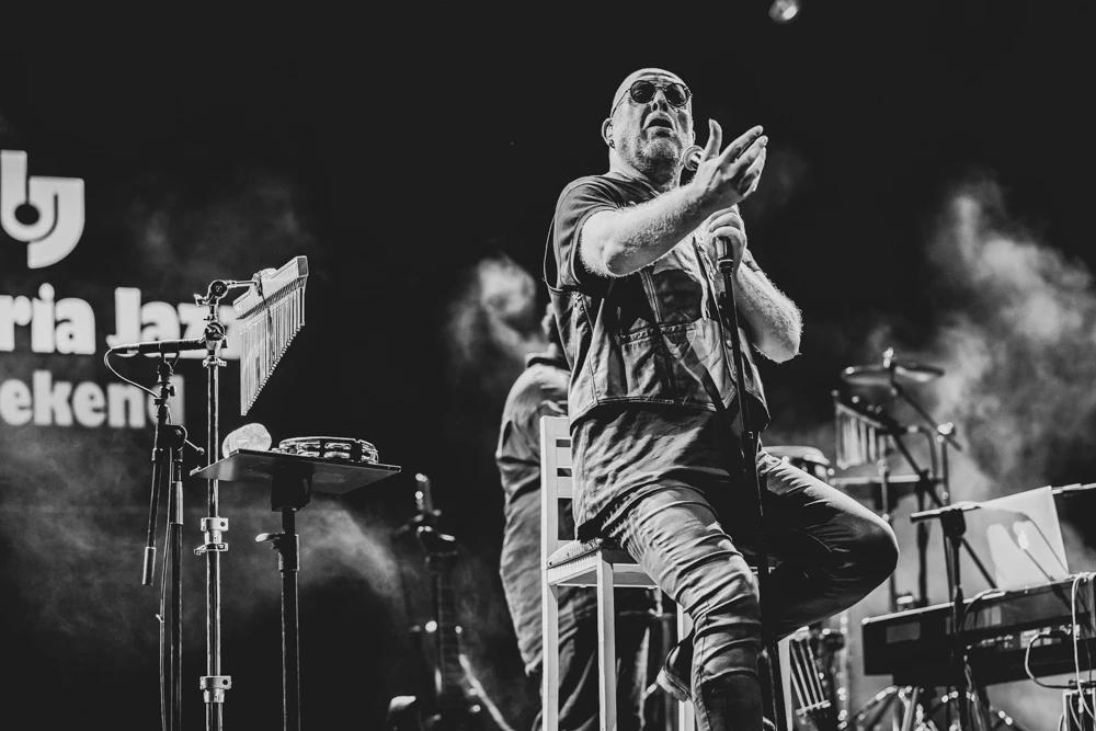 Seated on a stool, clapping in time through the smoke.