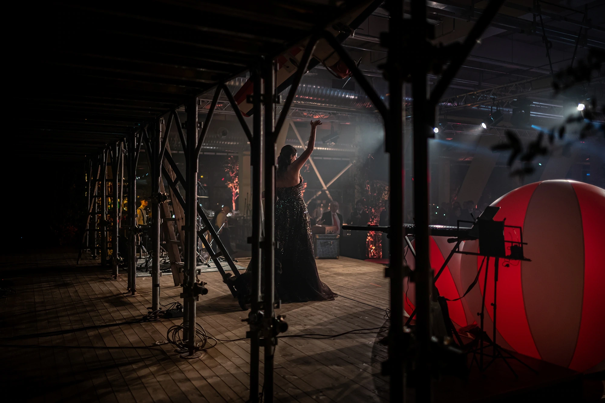 In an industrial space, a figure among the lights and a red balloon.
