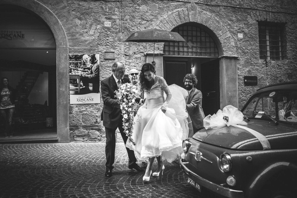In the street, the bride beside the decorated car.
