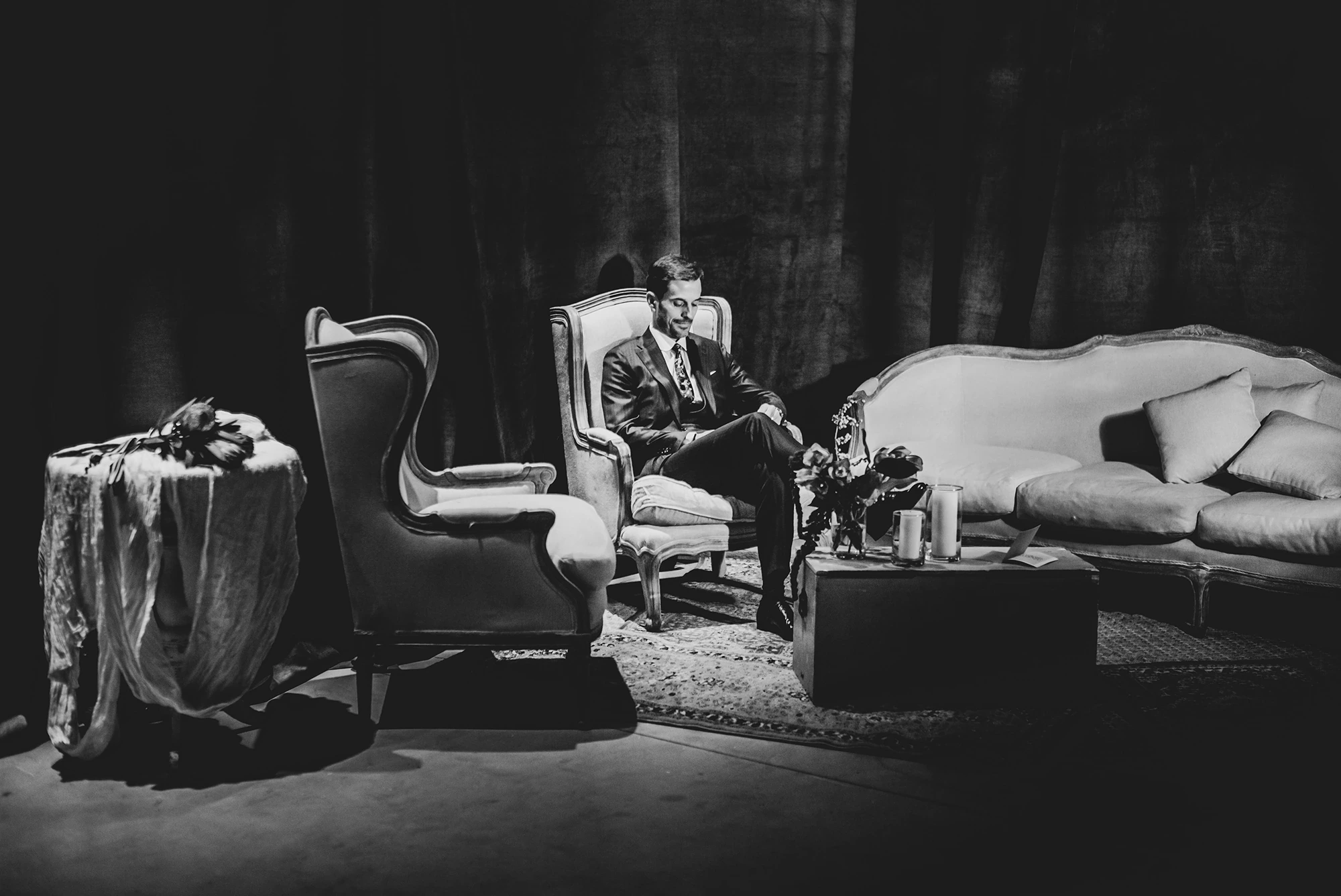 In the lounge, a man waits alone among the armchairs.