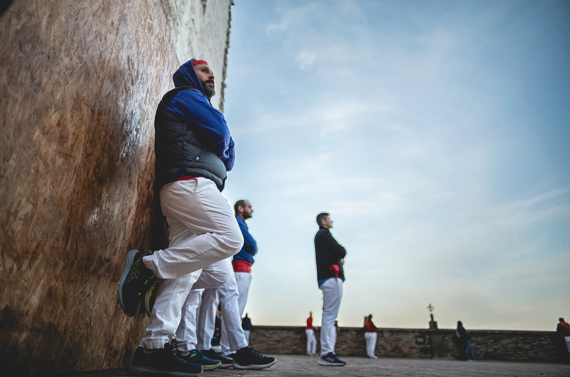 A man carried on another's shoulders, above the wall against the sky.