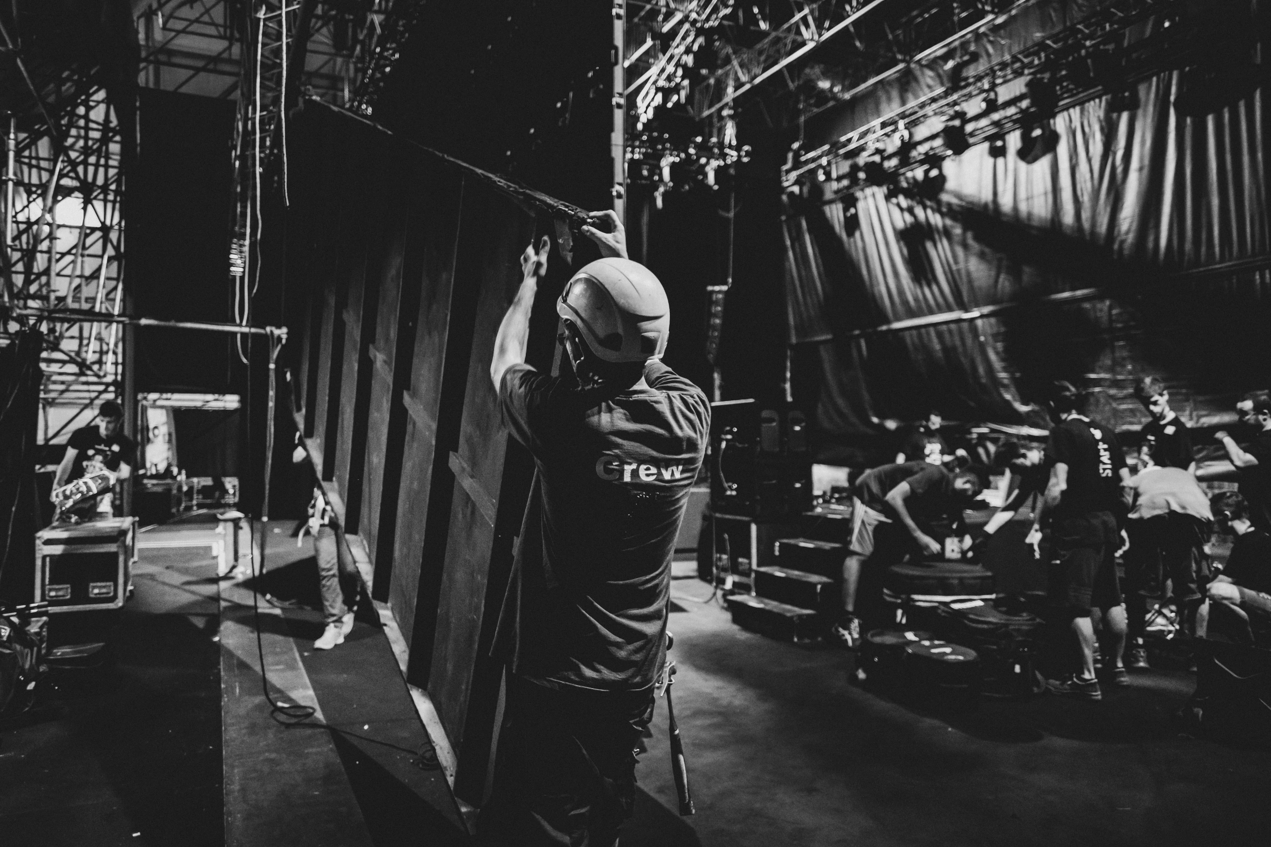 Backstage, a technician hauls on a line among the drapes.