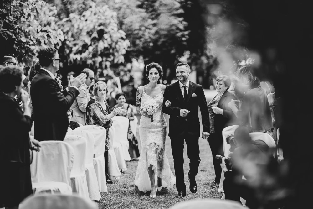 The couple pass between applauding guests, in the garden.