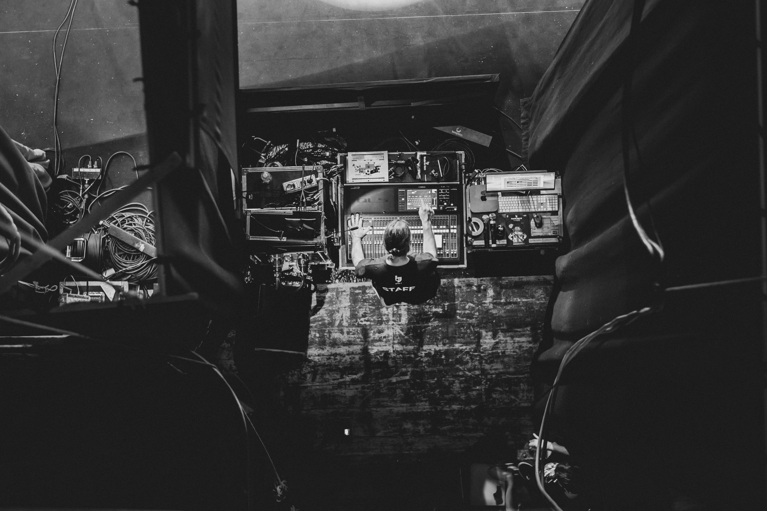 Beneath the stage cover, flight cases and cables of the rig.