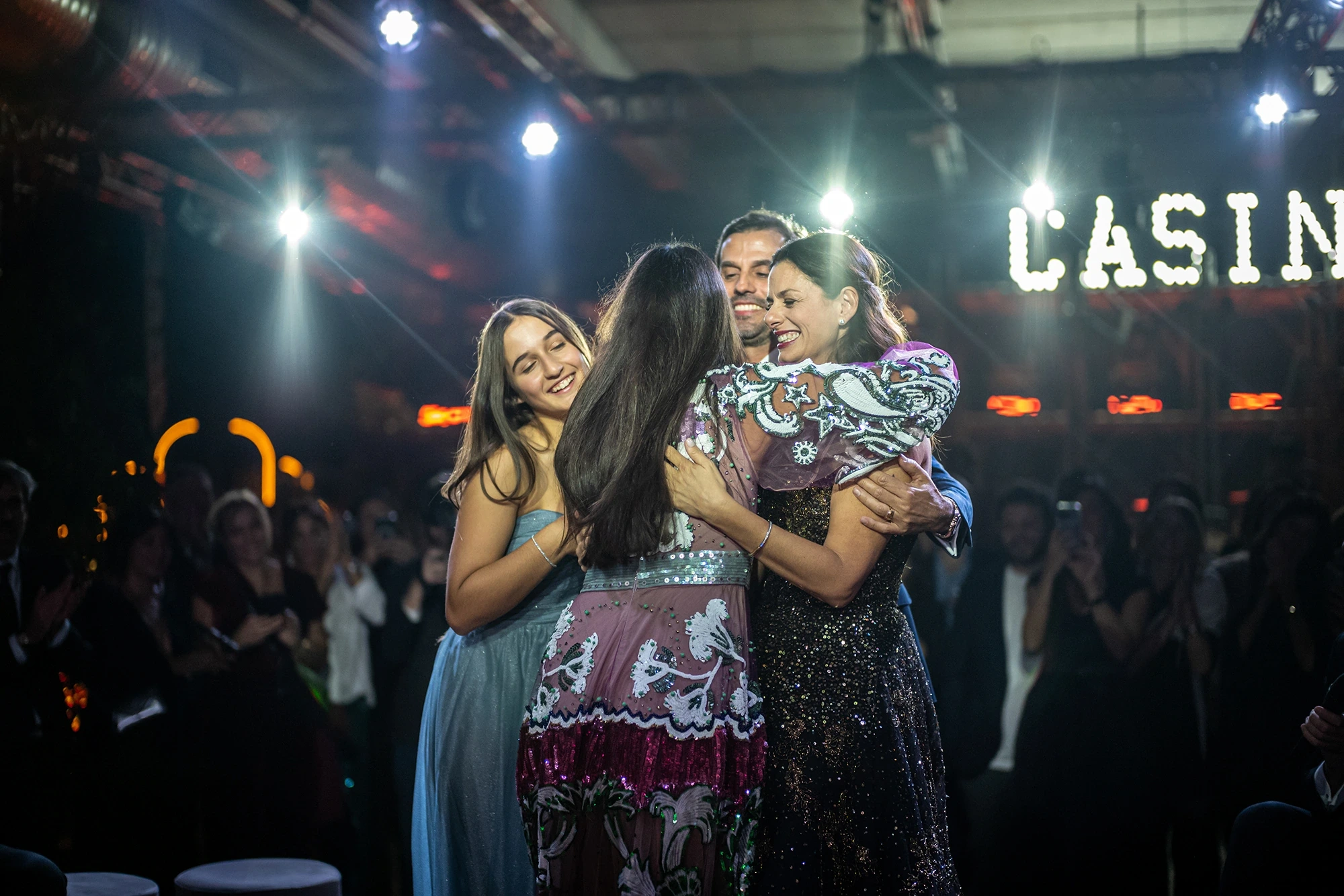 An embrace among the guests, beneath the illuminated letters.