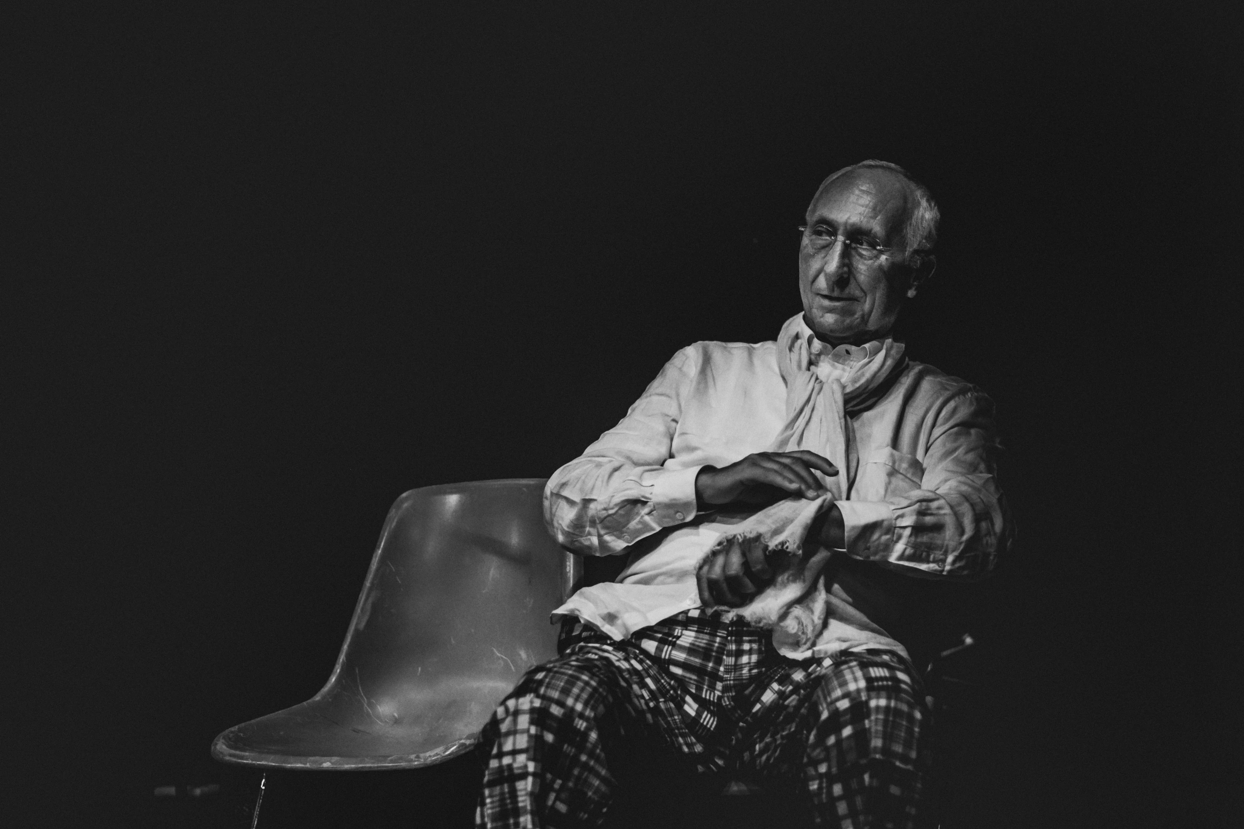Portrait of an elderly man seated on a chair, in a white shirt.
